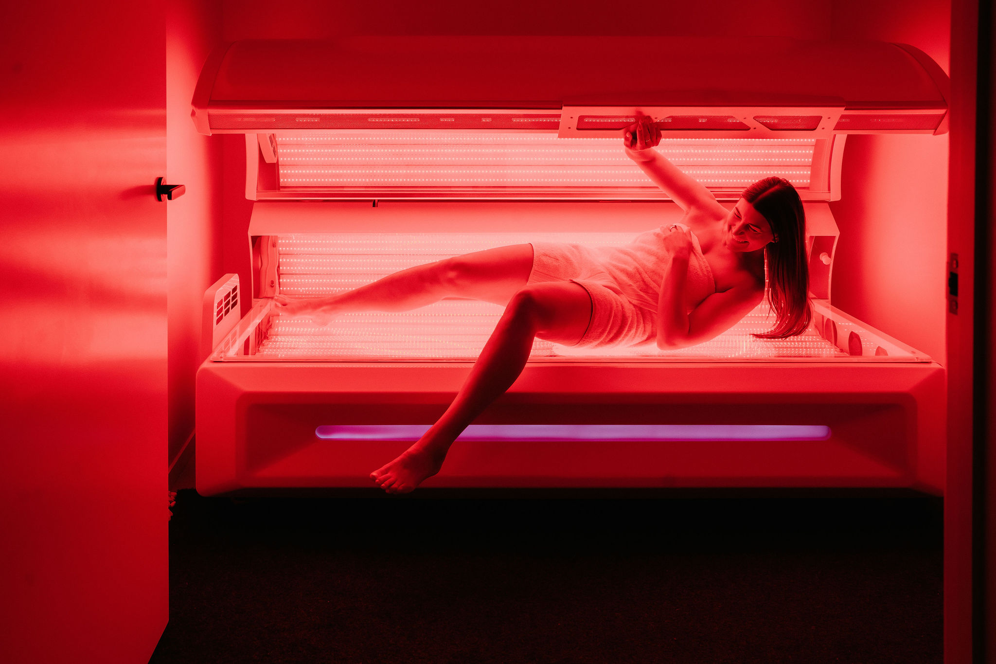 Woman relaxing inside the red light therapy pod at Gaia Wellness